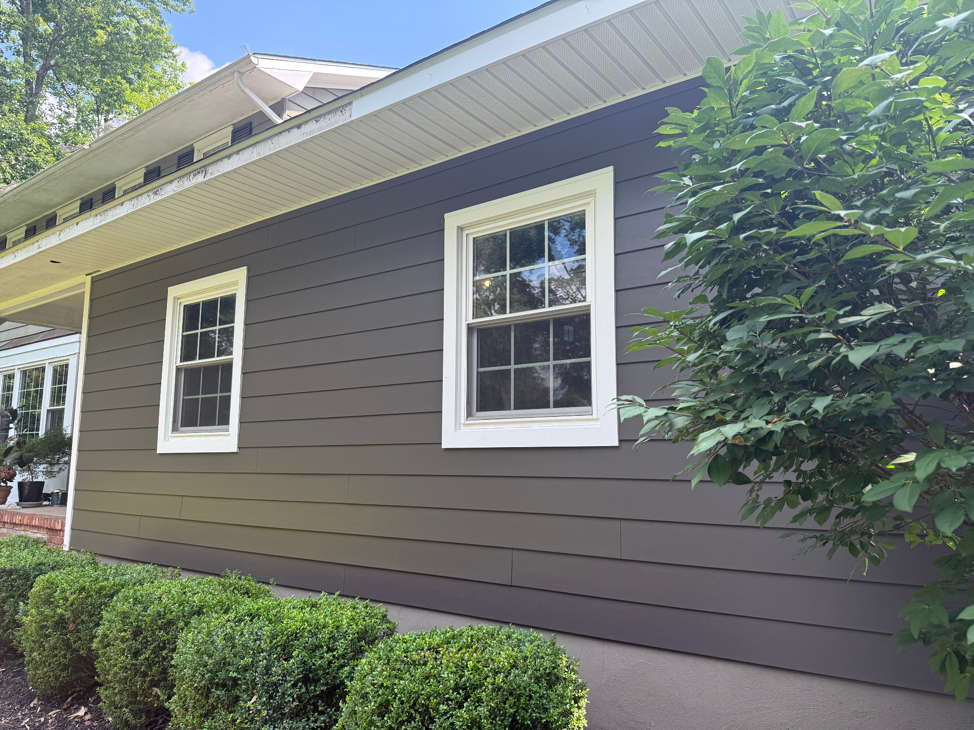 Close-up of finished dark gray Hardie lap siding with crisp white window trim