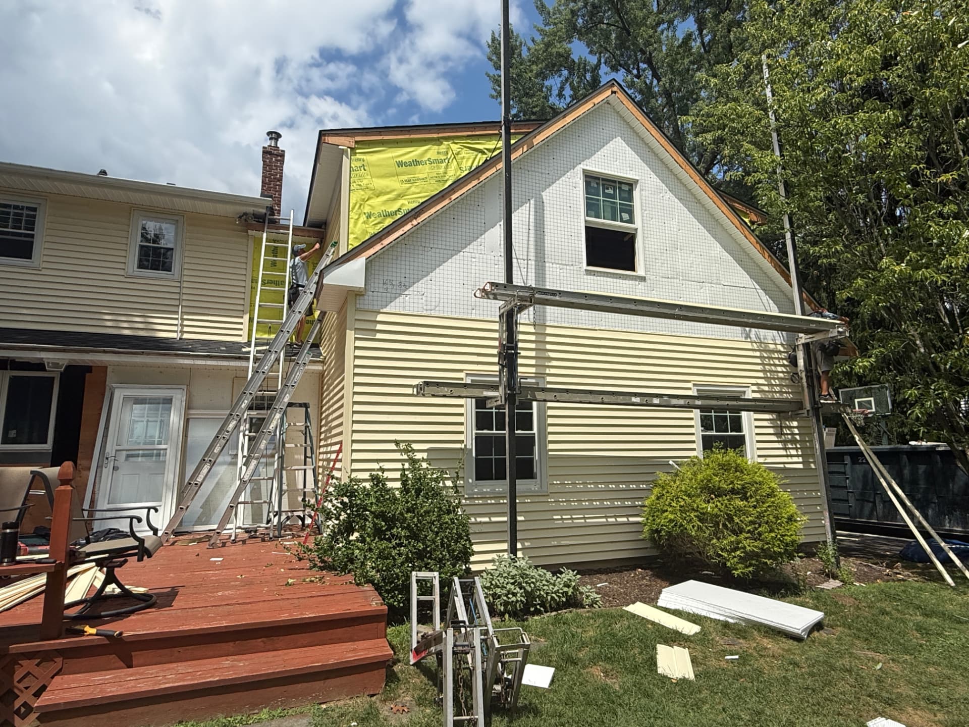 Crew removing old siding and installing WeatherSmart house wrap on a two-story home
